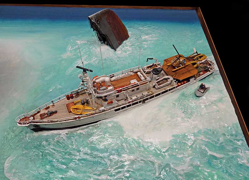 Maquette du navire Calypso de Cousteau naviguant sur une mer turquoise avec annexe et soucoupe plongeante