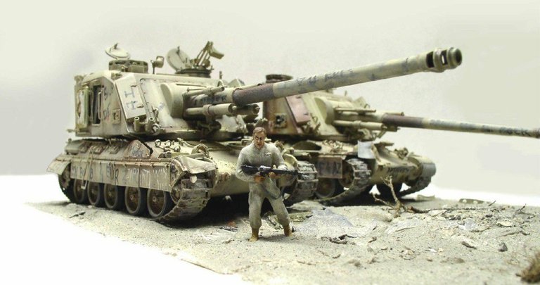 Deux maquettes d'automoteurs 155 AUF1 GCT et figurine de soldat armé sur diorama désertique