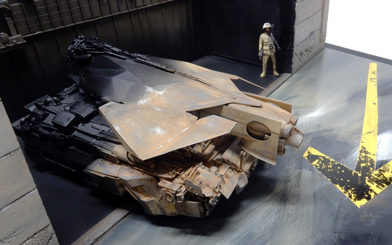 Maquette de véhicule de combat futuriste vieilli dans un hangar avec figurine de pilote