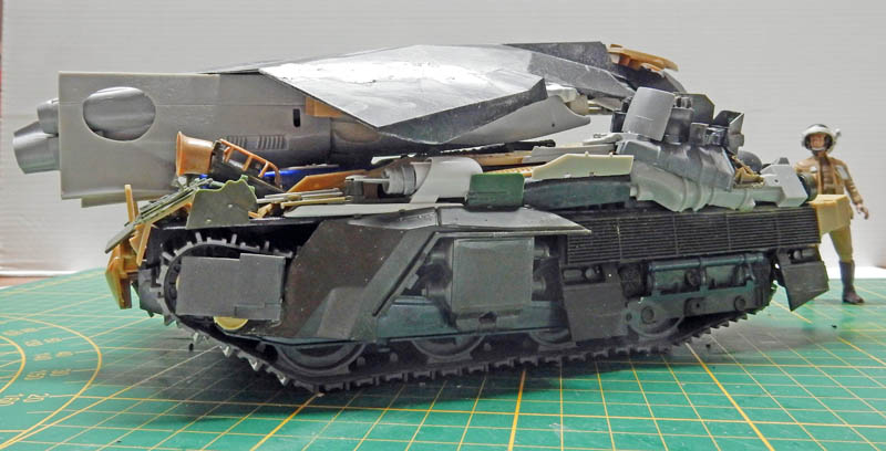Maquette de véhicule blindé chenillé futuriste vue de profil avec figurine de pilote à côté