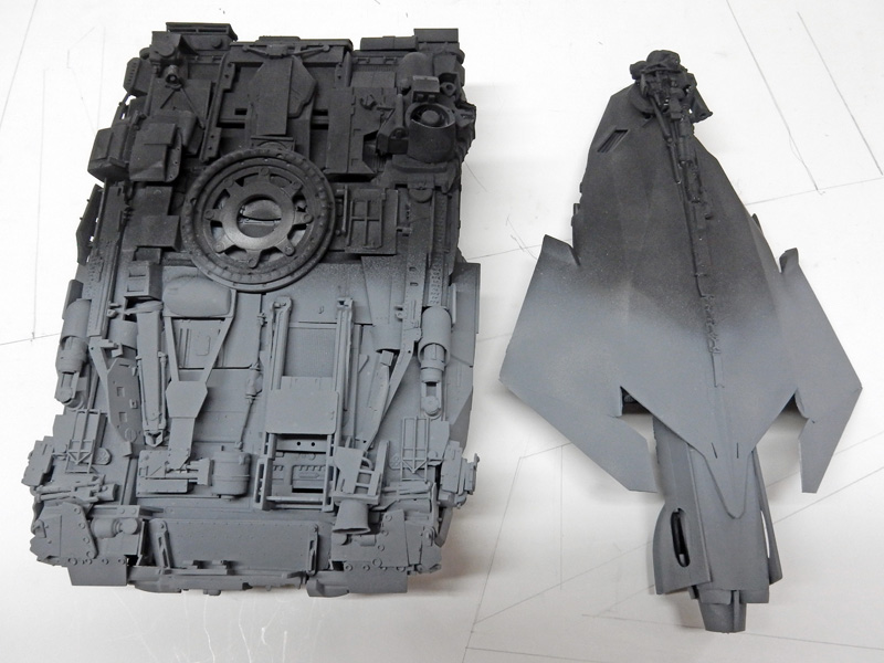 Pièces de maquette apprêtées en gris, coque de char et fuselage d'avion détaillés