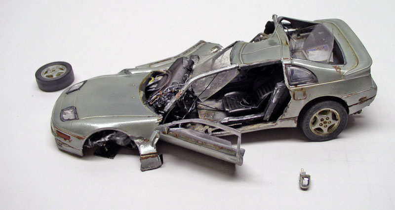 Maquette de voiture de sport grise accidentée, carrosserie déchirée et roue avant détachée