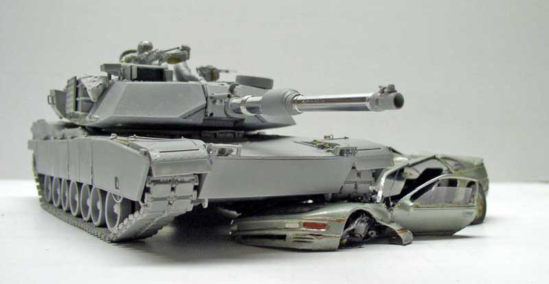 Maquette du char Abrams M1 A1 gris écrasant une voiture civile sous ses chenilles