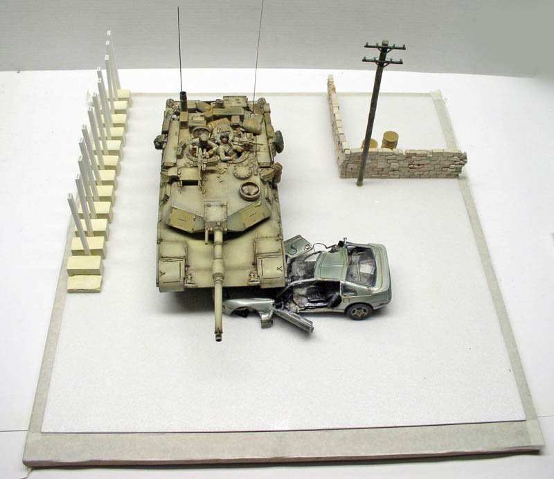 Maquette de char Abrams M1A1 écrasant une voiture sur un diorama avec mur et poteau