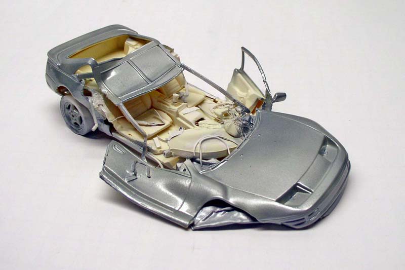 Maquette de voiture de sport argentée en cours d'assemblage, carrosserie et intérieur séparés