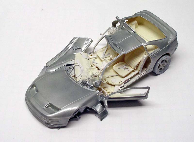 Maquette de voiture de sport argentée en cours d'assemblage avec habitacle beige apparent
