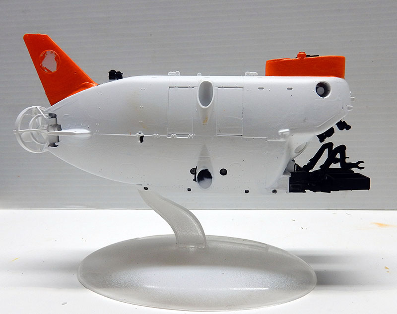 Maquette de sous-marin de poche blanc et orange sur socle transparent, vue de profil
