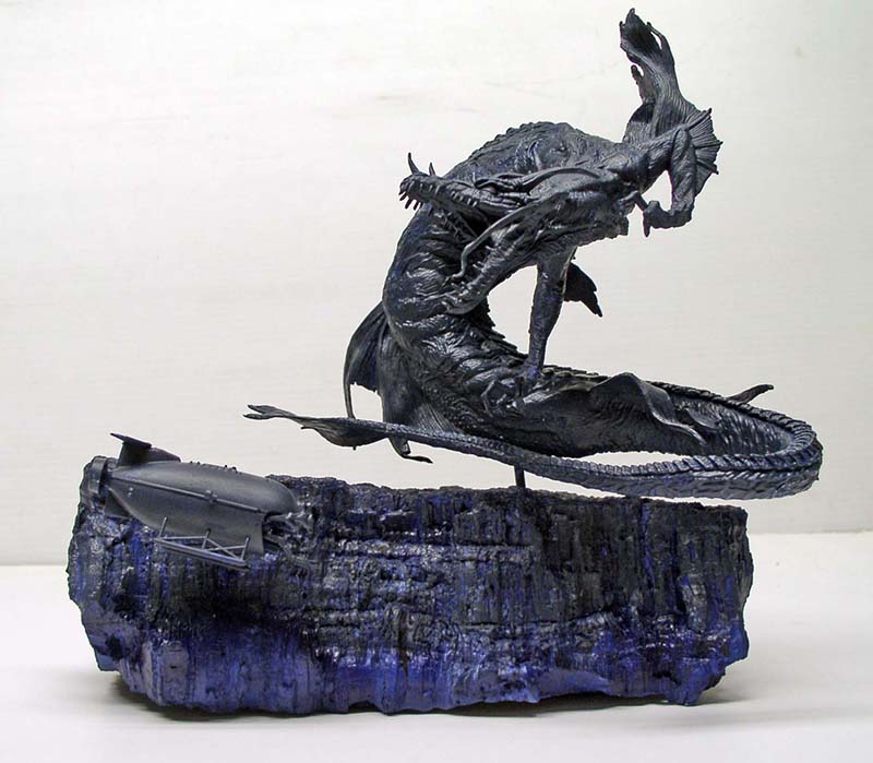 Maquette de créature abyssale sombre surplombant un sous-marin sur un diorama rocheux bleuté