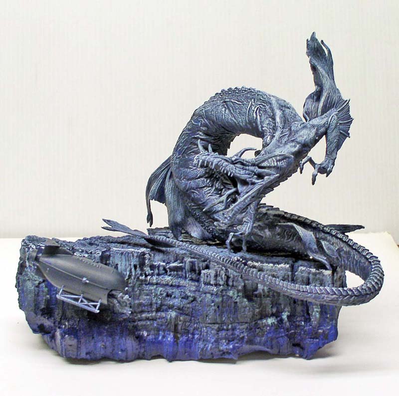 Maquette de créature abyssale dressée sur un rocher avec sous-marin, teintes bleu sombre