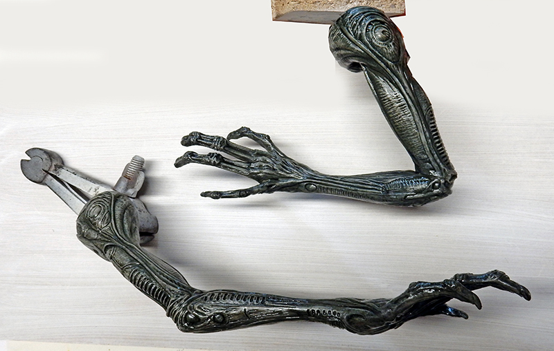 Deux bras de figurine Alien peints en vert sombre, fixés sur supports en bois pour montage