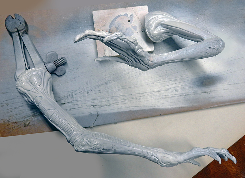 Bras et jambe de la maquette Alien 3 en résine grise non peinte sur établi
