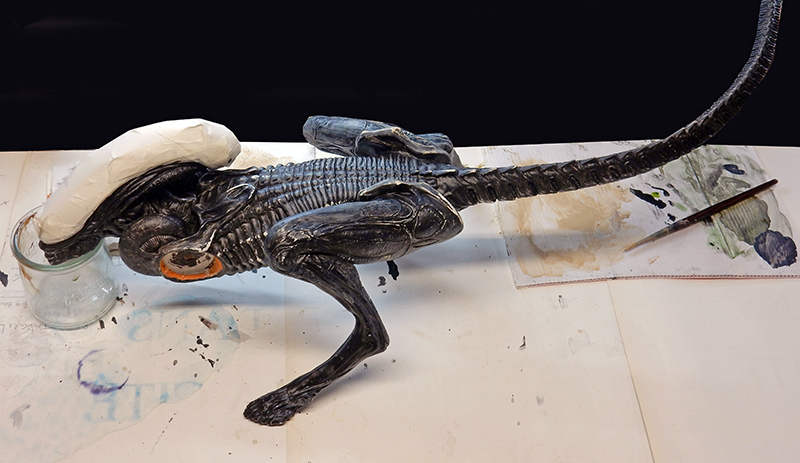 Maquette de l'Alien d'Alien 3 en cours de peinture sur établi avec pinceau