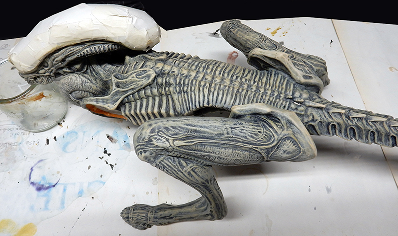 Maquette du xénomorphe Alien 3 en cours de peinture, tête protégée par du papier de masquage