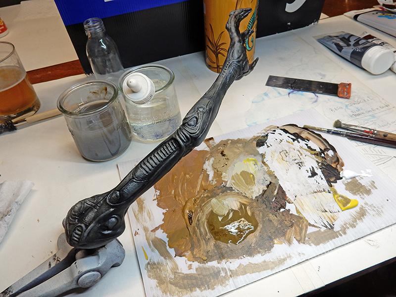 Maquette de bras d'Alien peinte en noir sur établi avec palette et pots de peinture