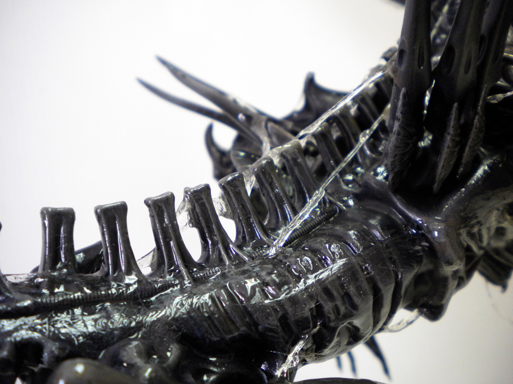Gros plan sur le dos noir laqué de la reine Alien, tubes dorsaux et carapace biomécanique