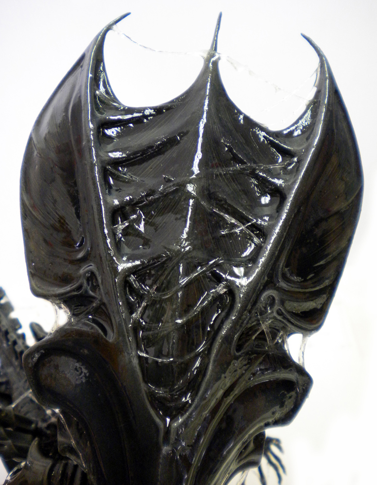 Gros plan sur la crête dorsale noire laquée de la reine Alien, filaments de bave brillants
