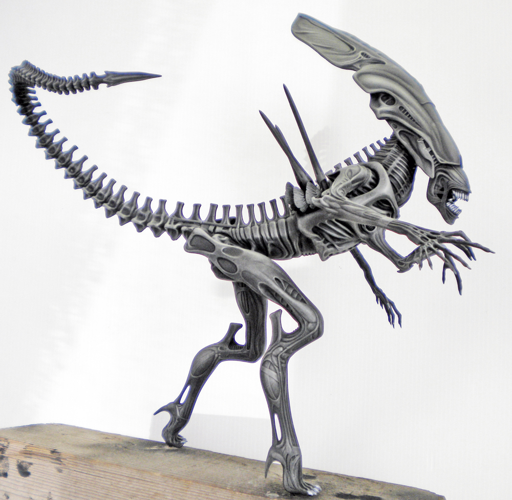 Maquette de la reine Alien peinte en gris, longue queue déployée, posée sur socle bois