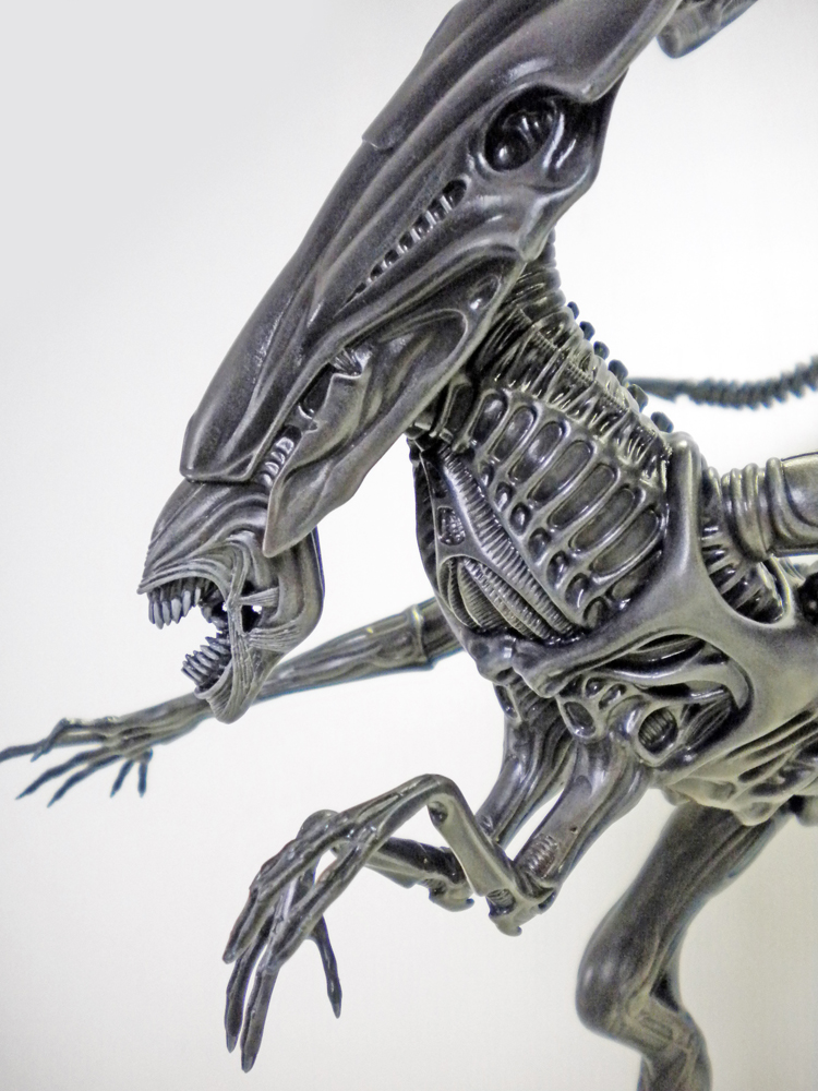 Maquette détaillée de la reine Alien gris métallisé montrant tête allongée, mâchoires et longs membres griffus