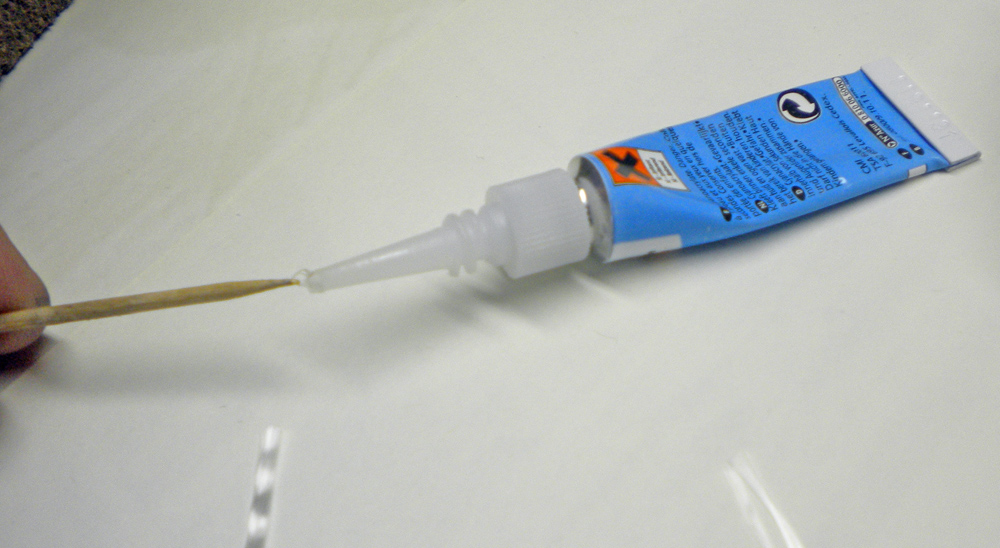Application de colle bleue avec un cure-dent depuis le tube à embout fin