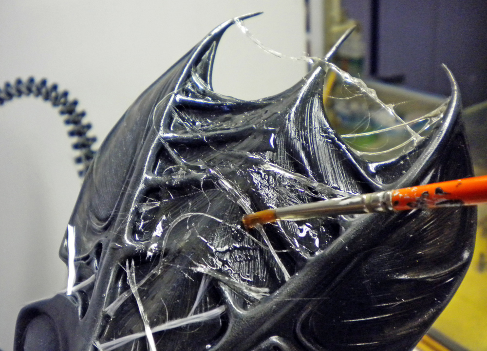 Application de filaments de colle au pinceau sur la tête noire de la reine Alien