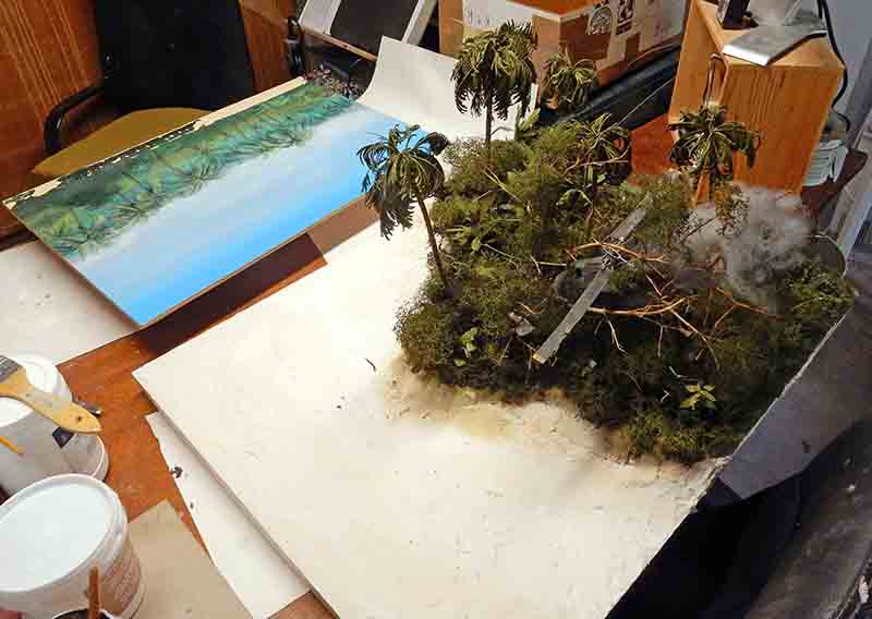 Diorama de jungle tropicale avec palmiers en cours de restauration sur un établi de maquettiste