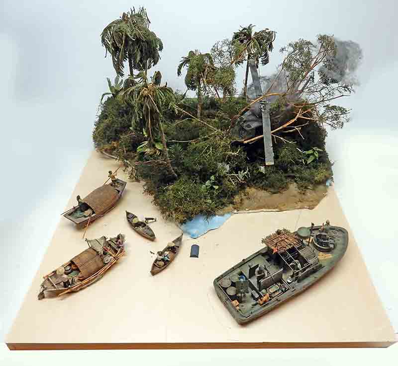Diorama en cours de restauration montrant une patrouilleur, sampans et berge tropicale sans eau