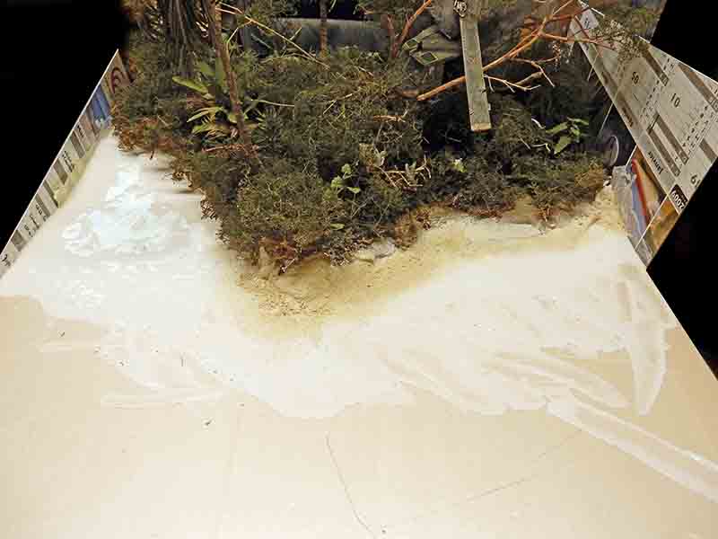 Diorama en cours de restauration montrant une berge végétalisée bordant un plan d'eau résiné