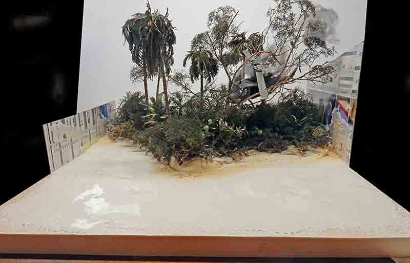 Diorama de jungle tropicale avec palmiers et hélicoptère sur socle, avant-plan de plage sableuse