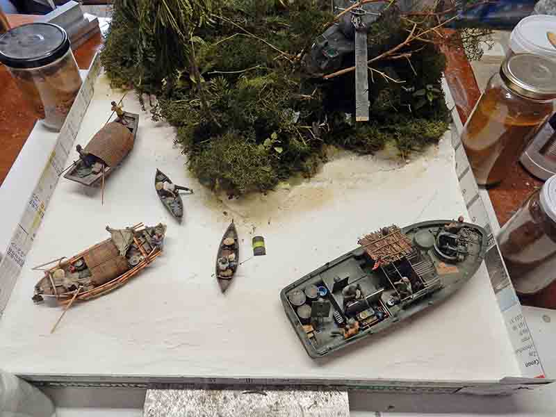 Diorama en cours de restauration montrant une vedette militaire et des barques sur une rivière