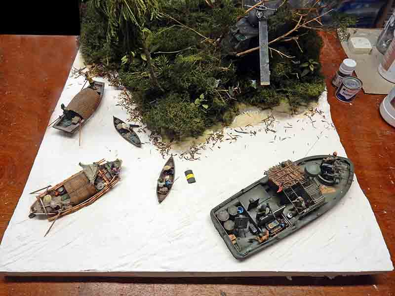 Diorama de rivière tropicale avec patrouilleur militaire et barques de pêcheurs près d'une berge végétalisée