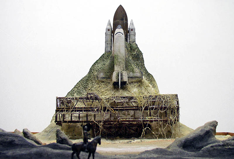 Maquette de diorama montrant une navette spatiale émergeant d'une colline végétalisée avec cavalier au premier plan