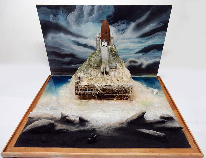 Maquette de navette spatiale émergeant d'un diorama prolongé par un décor peint en arrière-plan