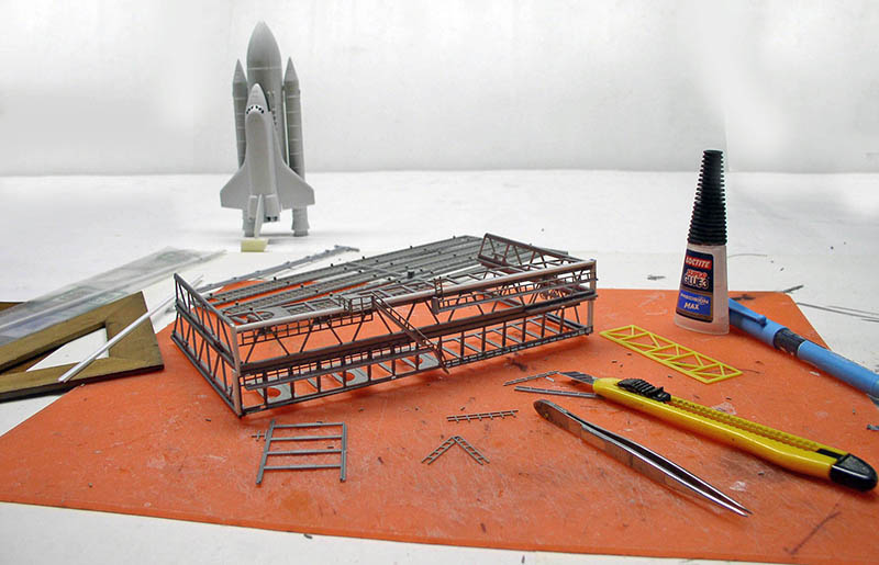 Structure métallique en cours d'assemblage avec maquette de navette spatiale, colle et outils de modélisme