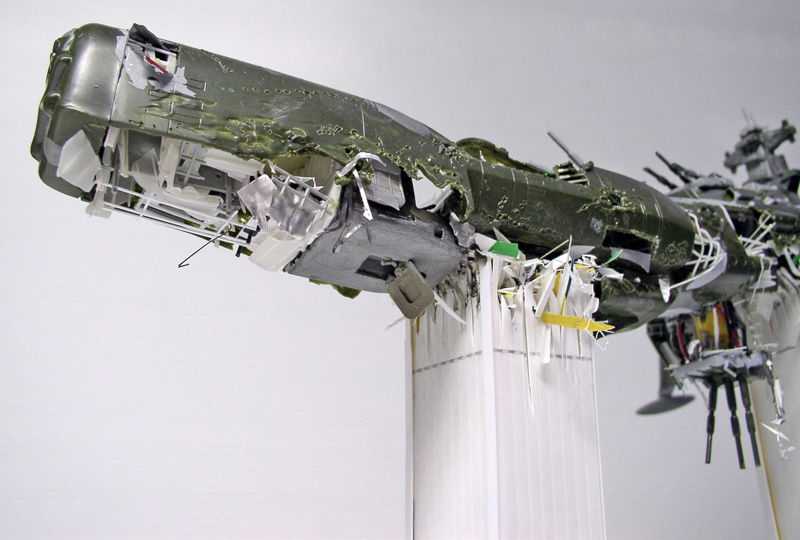 Maquette de l'Arcadia vert au fuselage déchiré, débris suspendus simulant le crash