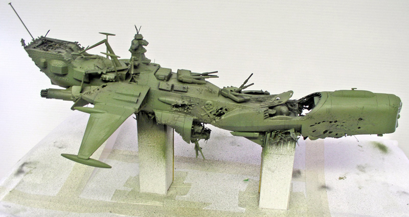Maquette du vaisseau Arcadia d'Albator en apprêt vert, posée endommagée sur une base