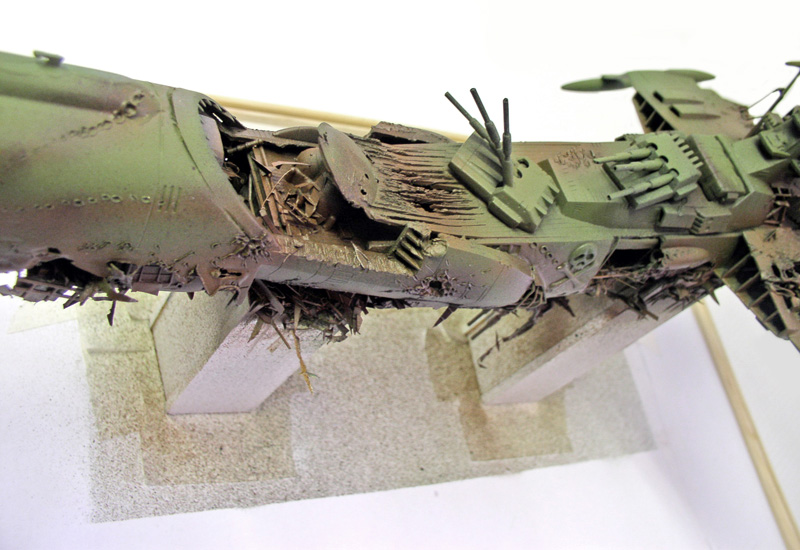 Maquette verte du vaisseau Arcadia avec coque éventrée montrant la structure interne détaillée du crash