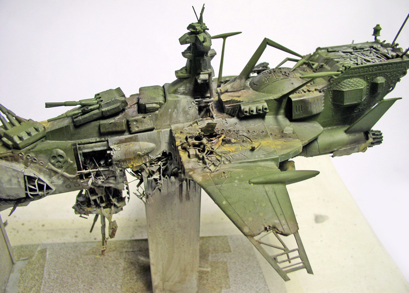 Maquette du vaisseau Arcadia vert accidenté, coque éventrée et superstructure détaillée, posé sur socle