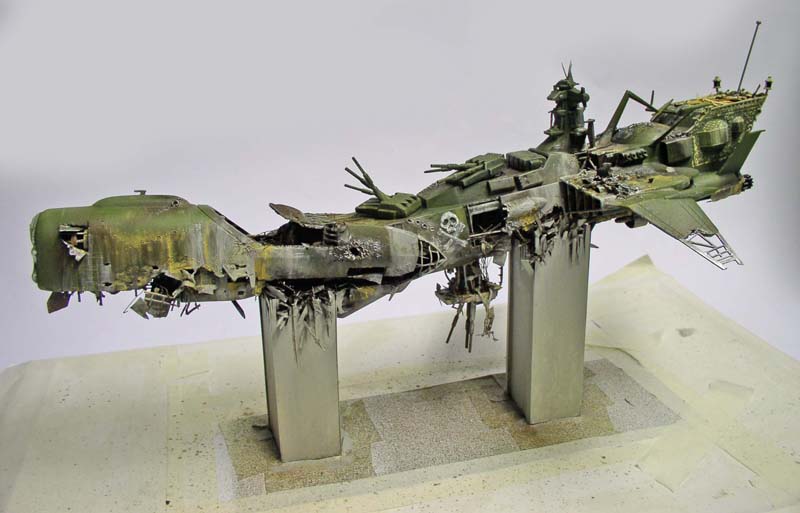 Maquette du cuirassé Arcadia vert, coque brisée en deux après le crash, sur supports