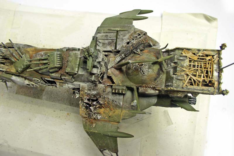 Maquette du vaisseau Arcadia vue de dessus, coque verte vieillie et endommagée après le crash