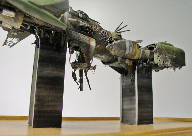Maquette de l'Arcadia d'Albator écrasé, coque verte endommagée posée sur deux supports
