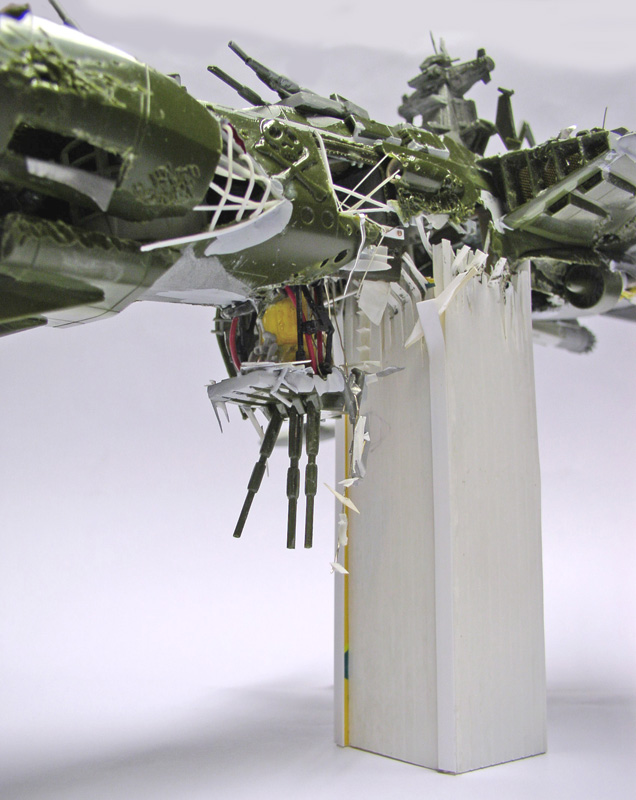 Maquette de l'Arcadia vert encastré dans une tour blanche, structure éventrée et câbles apparents simulant le crash