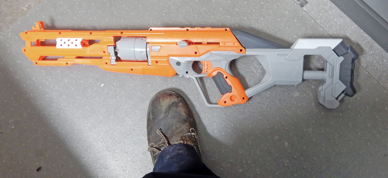 Pistolet Nerf orange et gris posé au sol près d'un pied avant transformation cosplay