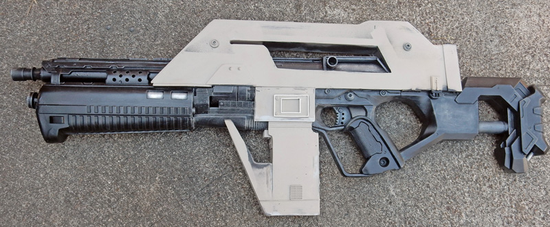Réplique de fusil futuriste pour cosplay, en cours de fabrication, posée au sol