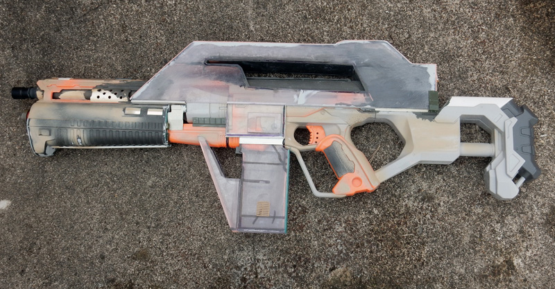 Réplique de fusil futuriste pour cosplay en cours de patine, posée sur le sol