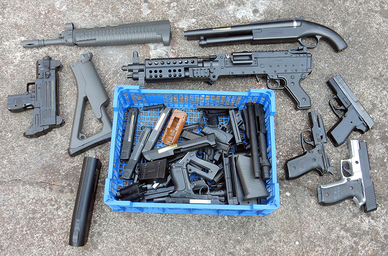 Répliques d'armes factices en plastique et pièces détachées dans une caisse bleue pour cosplay