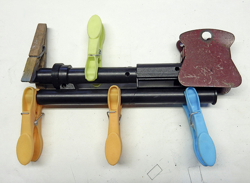 Pièces d'arme de cosplay peintes en noir maintenues assemblées par des pinces à linge colorées pendant le collage