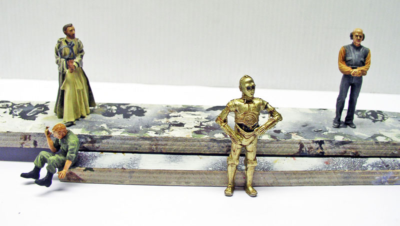 Figurines peintes de personnages dont un droïde doré C-3PO posées sur des socles