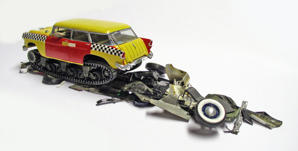 Maquette de break américain jaune à chenilles écrasant l'épave d'une voiture détruite