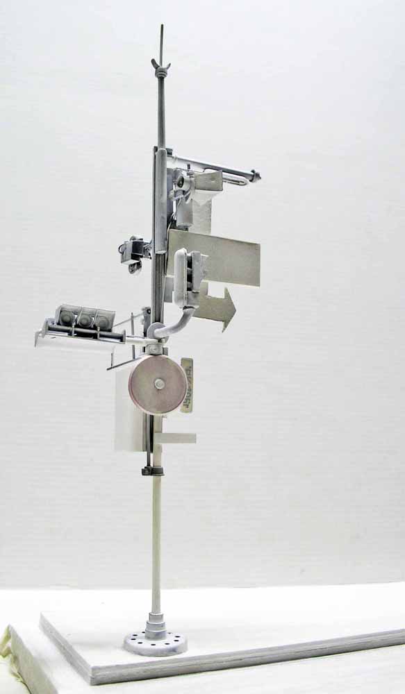 Maquette en cours de montage sur tige verticale, pièces grises non peintes assemblées autour d'un disque