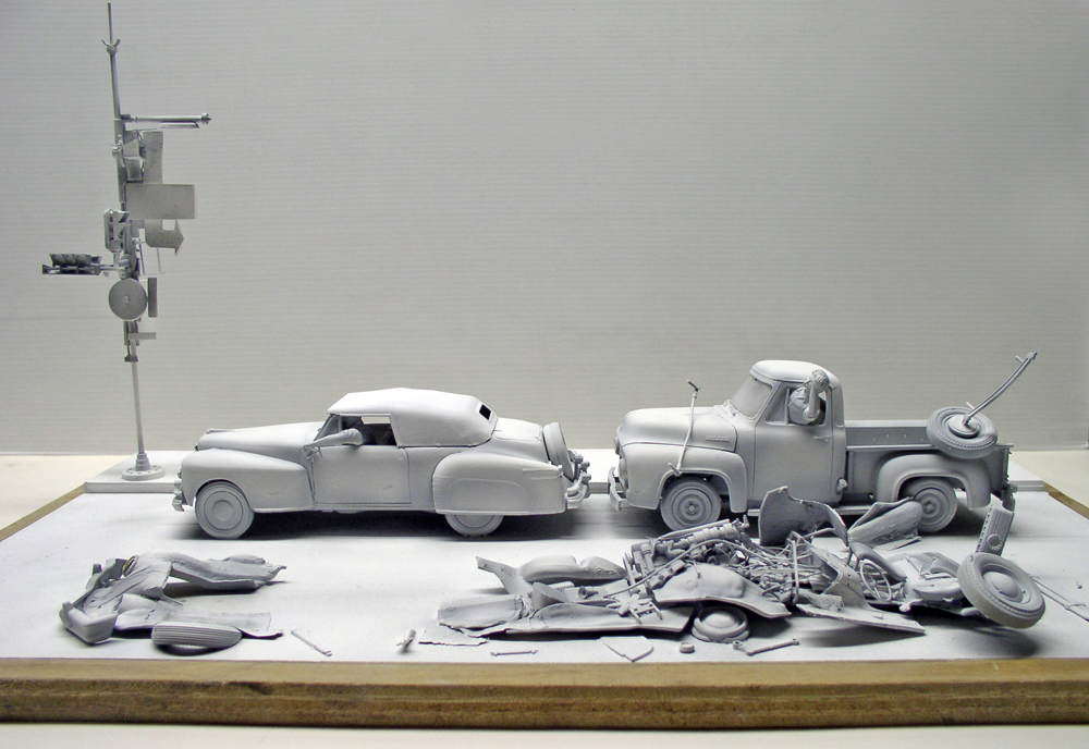 Maquettes grises non peintes d'une voiture et d'un pick-up avec pièces détachées éparpillées sur un socle